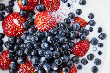 Strawberries, blueberries and milk in a white bowl