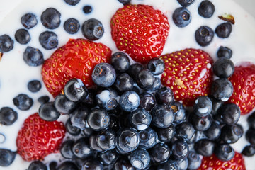 Strawberries, blueberries and milk in a white bowl