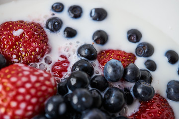 Strawberries, blueberries and milk in a white bowl
