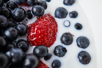 Strawberries, blueberries and milk in a white bowl