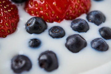 Strawberries, blueberries and milk in a white bowl