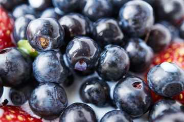 Strawberries, blueberries and milk in a white bowl
