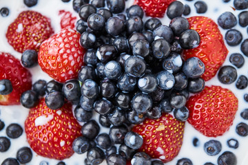 Strawberries, blueberries and milk in a white bowl