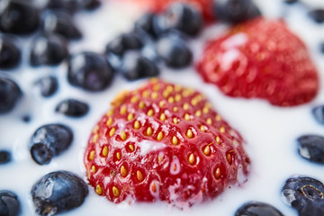 Strawberries, blueberries and milk in a white bowl