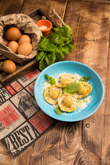plate with ravioli, basil and parmesan cheese flakes. vertical