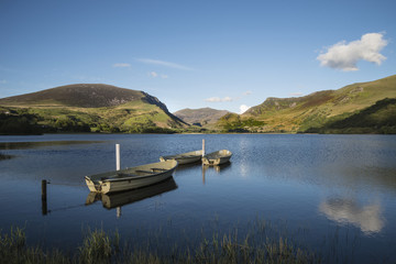 Stunning dramatic stormy sky formations over breathtaking mountain lake landscape with rowing boats in foreground