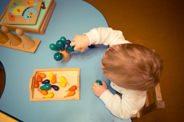 a little boy developing lessons for kids collects wooden designer