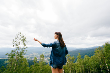 Woman in wild nature asking sky for blessing and enjoying  nature greatness. Relaxation, meditation, harmony of inner life and mind. Unity of human and world. Exaltation of heart and consciousness.