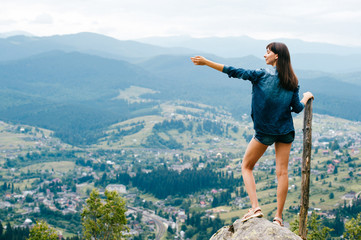 Lonely beatiful girl with long hairs in summer clothes at top of mountain pulling her hand to sky. Asking for blessing. Freedom and greatness. Reflexion. Contemplation.  Nature landscape. Sightseeing