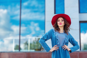 Young woman in red hat, posing in blue dress