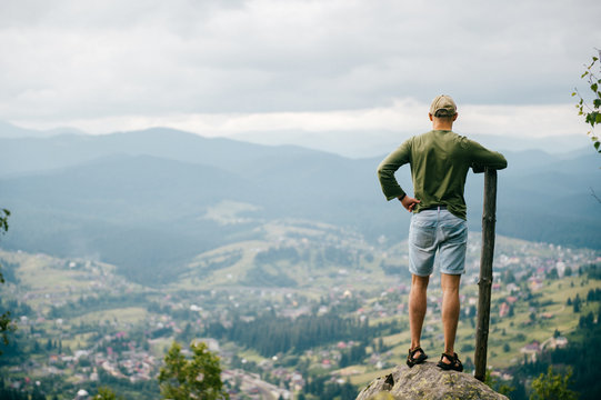 Strong man with wooden staff stick looking far at horizon. Primal leader. Masculine power. Discover, coquer. Kingdom lord. Edge of world. Nature spirit salutation. Rude strength. Reaching highest peak