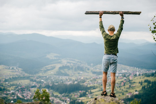 Strong man with wooden staff stick looking far at horizon. Primal leader. Masculine power. Discover, coquer. Kingdom lord. Edge of world. Nature spirit salutation. Rude strength. Reaching highest peak