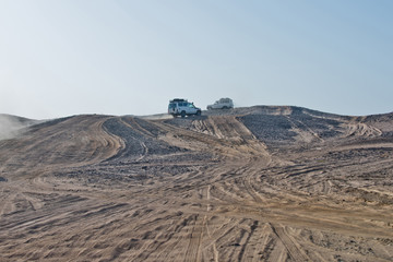 Wheel tracks on sand dunes and cars driving in desert