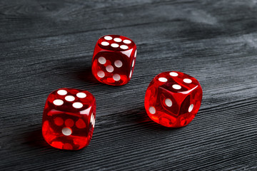 risk concept - playing dice at black wooden background. Playing a game with dice. Red casino dice rolls. Rolling the dice concept for business risk, chance, good luck or gambling