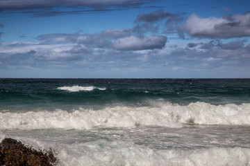 Breaking waves of the Indian Ocean at the Wild Coast of South Africa with cloudy sky