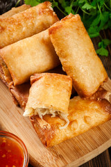 Spring rolls with chicken and vegetables on chopping board