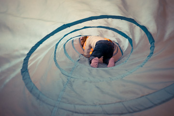 a little boy developing lessons for toddlers crawling through the "tube" tunnel