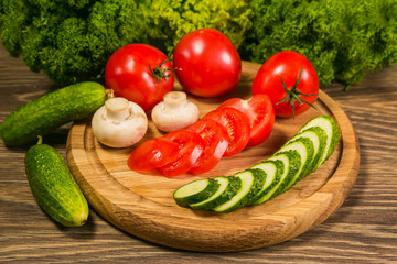 Fresh vegetables. Tomatoes, cucumbers and mushrooms on a wooden board