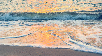 abstract background - orange sunrise reflecting off the waves crashing on the shore