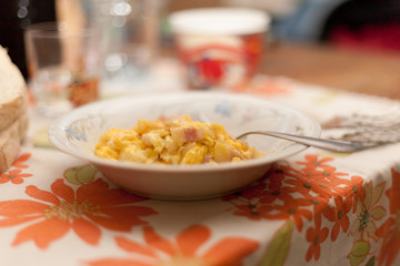 Scrambled eggs and bacon in ceramic dish with fork an Italian Food Made in Italy with Flower tablecloth