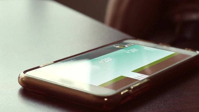 Smartphone with generic video game playing on the screen in cafe