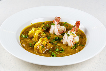 Prawn curry on white plate served with parsley