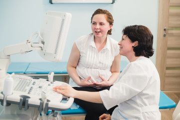 Fototapeta premium Doctor showing baby ultrasound image on computer to pregnant woman
