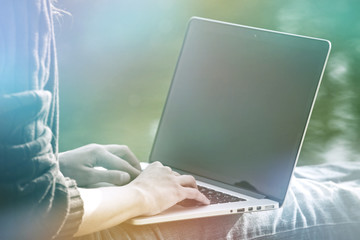 Fototapeta premium girls hands holding laptop in sunlight on natural summer water background