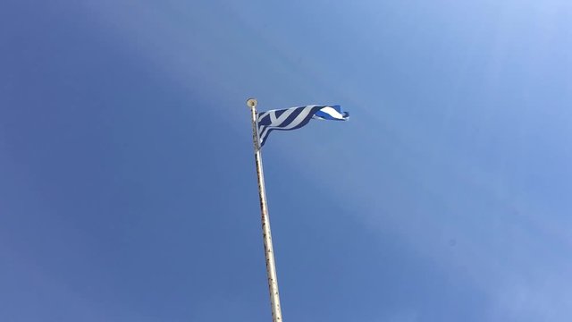 Greek national flag flying on mast against blue sky. Dodecanese Islands, Rhodes Islands, Greece, Europe