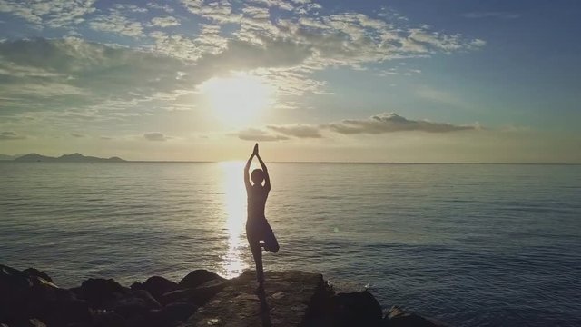 Drone Removes from Girl Holding Yoga Pose against Sunrise Path