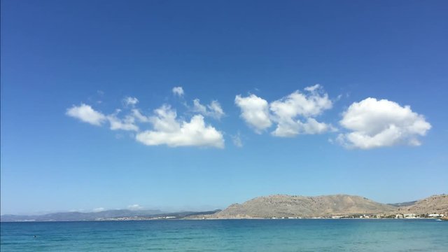Time-lapse video of tropical clouds on blue sky with azure blue sea below. Island of Rhodes, Greece