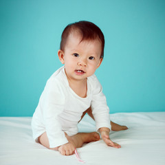 Fototapeta premium A crawling baby in diaper with blue background (soft focus on the eyes)