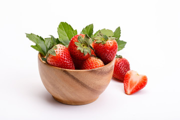 Red berry strawberry in a wooden bowl isolated on white background. Strawberries with leaves in a wooden bowl. Isolated