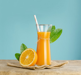 Glass of fresh orange juice on wooden table, Fresh fruits Orange juice in glass with group of orange on blue background, Selective focus on glass