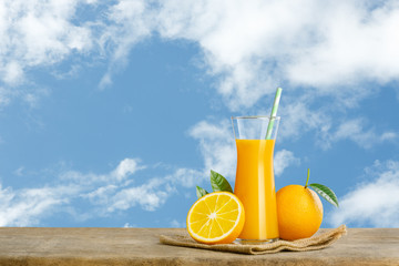 Glass of fresh orange juice on wooden table, Fresh fruits Orange juice in glass with group on blue sky background with copy Space for your text.