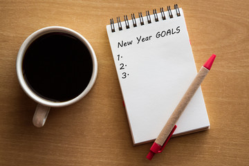 New year goals list- handwriting on a notebook with cup of coffee