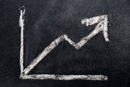 White chalk draw as upward arrow graph on black board background (Concept for sale, profit, cost of company in uptrend)