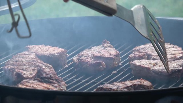 Man's hands cooking steak on grill