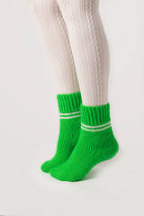 Female legs in white stockings and green knitted socks.
