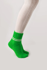 Female legs in white stockings and green knitted socks.