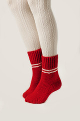 Female legs in white stockings and red knit socks.