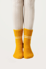 Female legs in white stockings and yellow knitted socks.