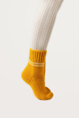 Female legs in white stockings and yellow knitted socks.