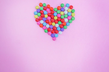 Colorful candies heart shape on pink