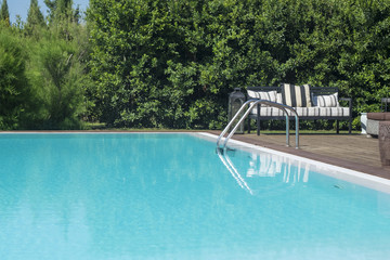 Quiet blue outdoor swimming pool with ladder