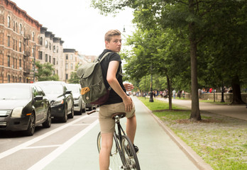 Naklejka premium Young hipster riding bike looking back in the city