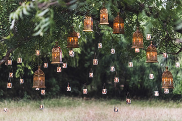 Night wedding ceremony with a lot of vintage lamps and candles on big tree