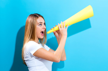 Young woman holding a paper megaphone on a blue background