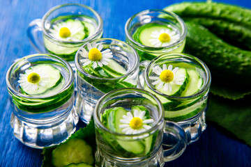 Cucumber water in six little mason glass jar on blue background. Rustic. Detox