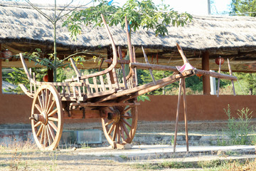 The old wooden cart is located outdoor.